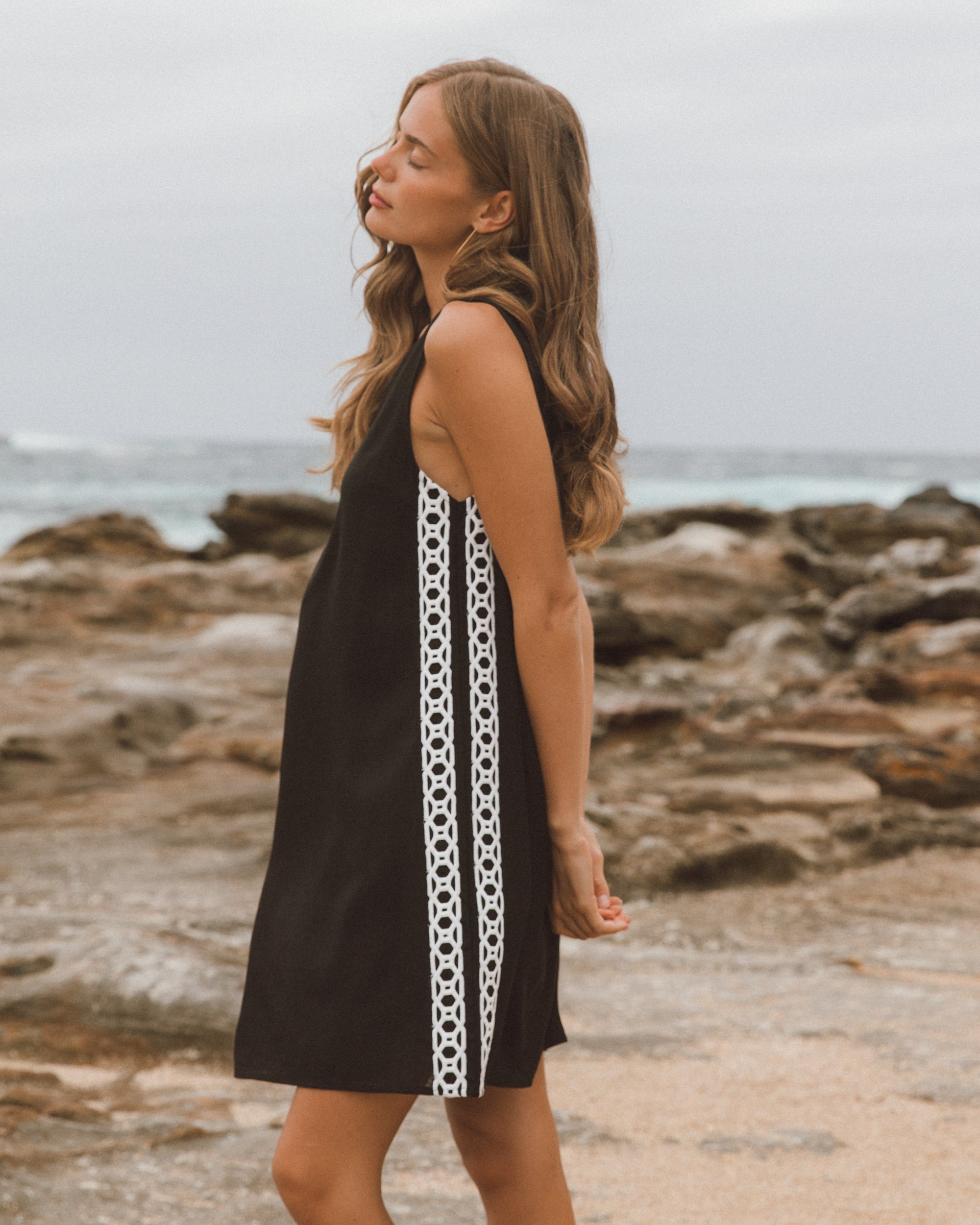 Woman wearing a black dress with white pattern on a rocky beach