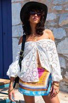 White broidery anglaise blouses on model wearing a black hat and colored skirt