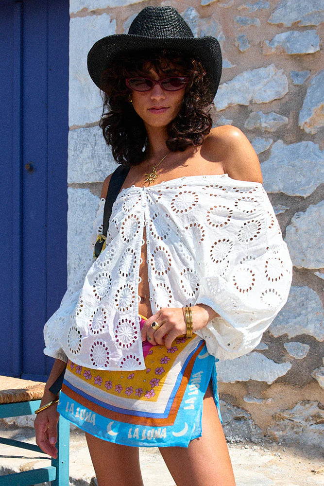 White broidery anglaise blouses on model wearing a black hat and colored skirt