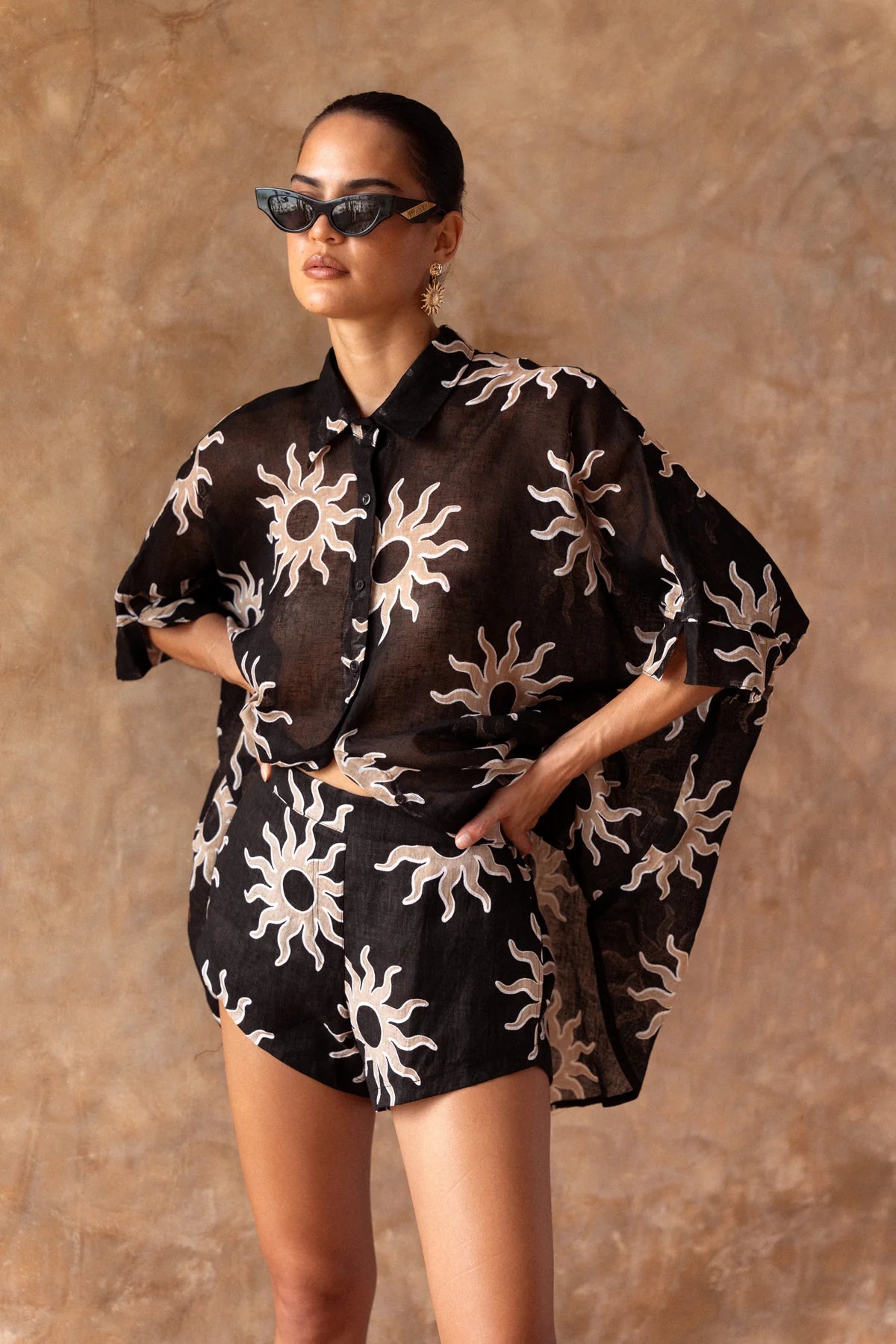 Woman wearing a black outfit with white patterns against a brown background