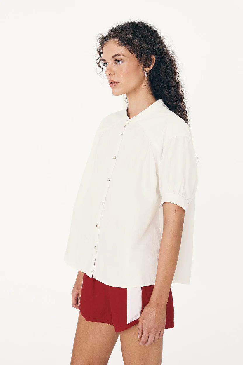 Woman wearing a white blouse and red shorts on a white background