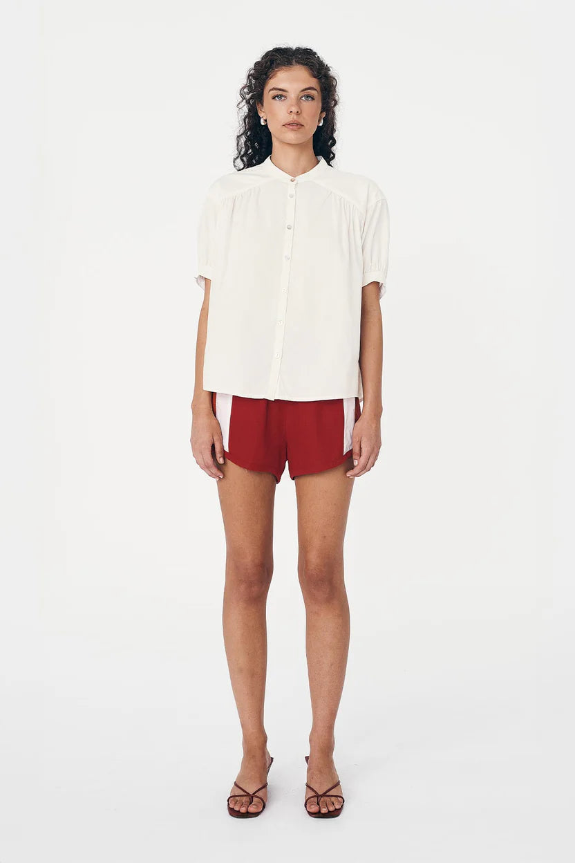 Woman wearing a white blouse and red shorts on a white background
