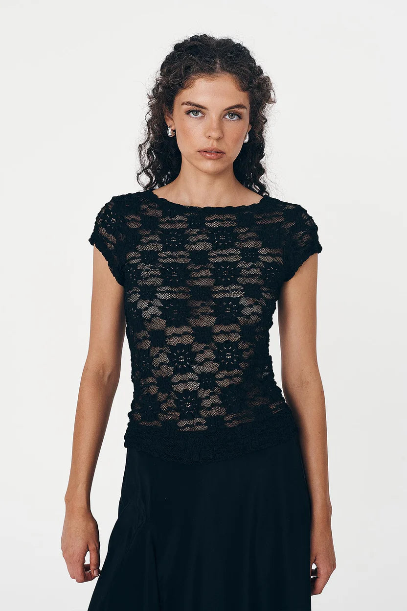 Woman wearing a black lace top against a white background