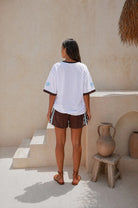 Person wearing a Palm Collective Maroc t-shirt in white with brown sleeve trim and brown and blue decorations