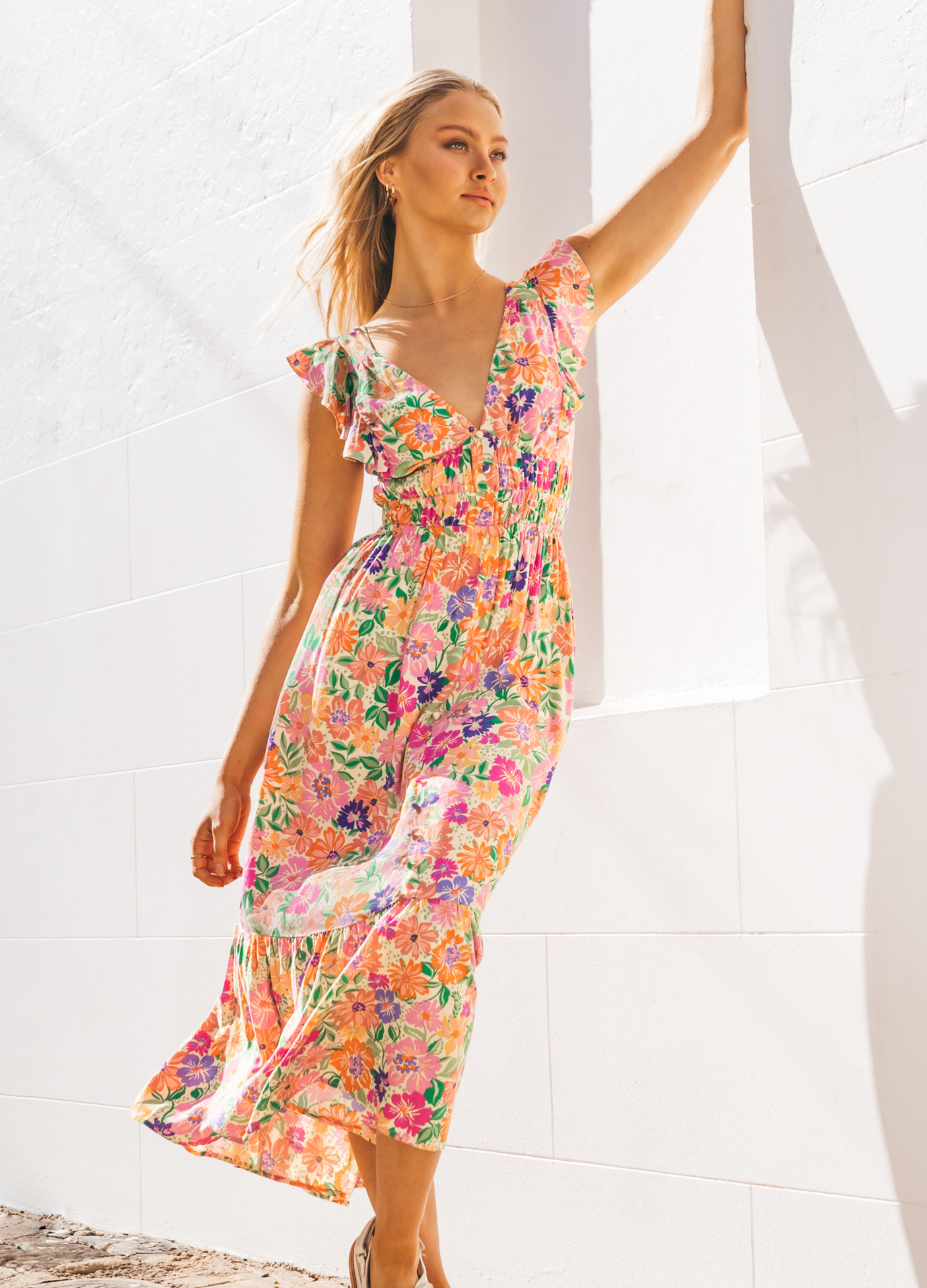 Model wearing bright floral colour dress with cut out at the back and buttons at the front
