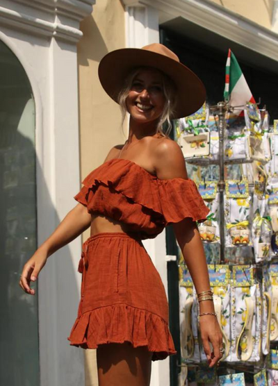 Model wearing rust colour cropped top with frill details