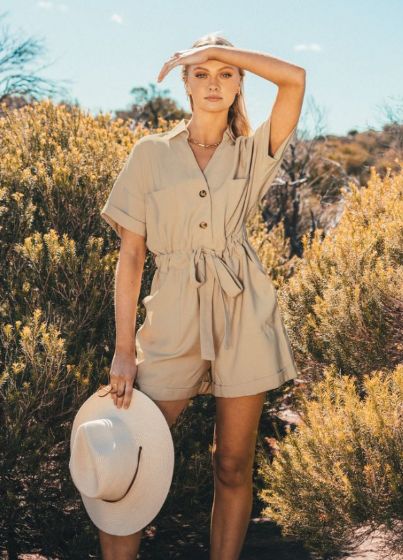 Model wearing safari style playsuit with functional buttons, collar and self belt