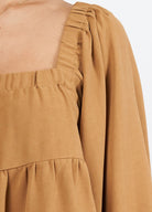 Woman wearing cinnamon colour trapeze top