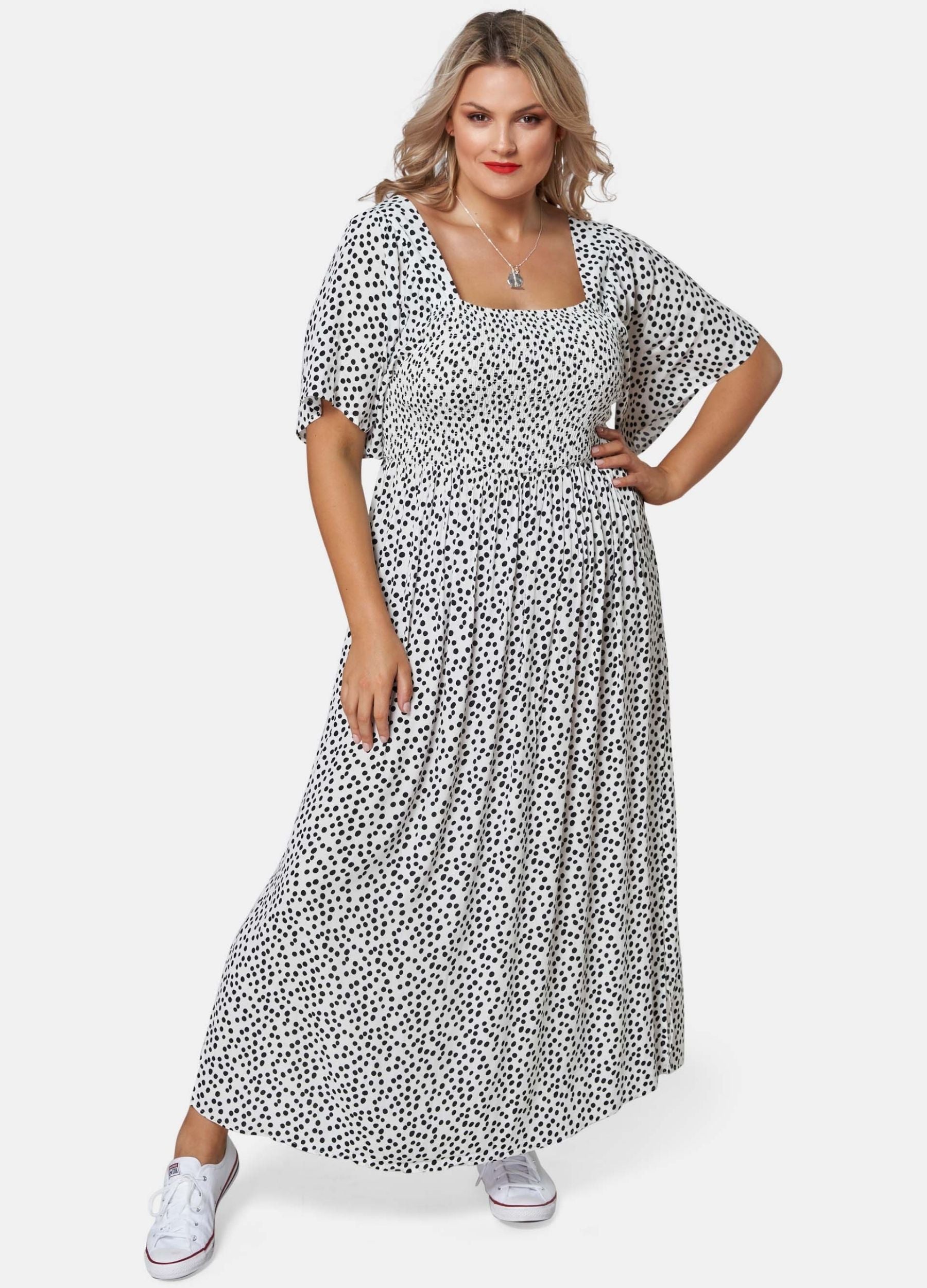 Blonde woman wearing black and white spot maxi dress