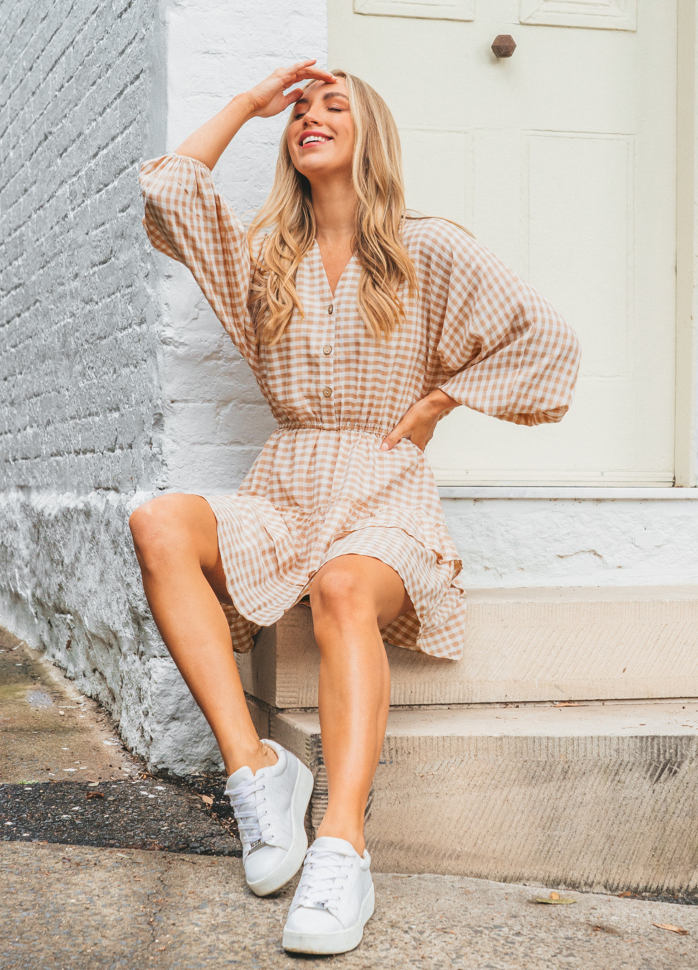 Model wearing neutral and white gingham shirt dress with functional button placket and elasticated waistband