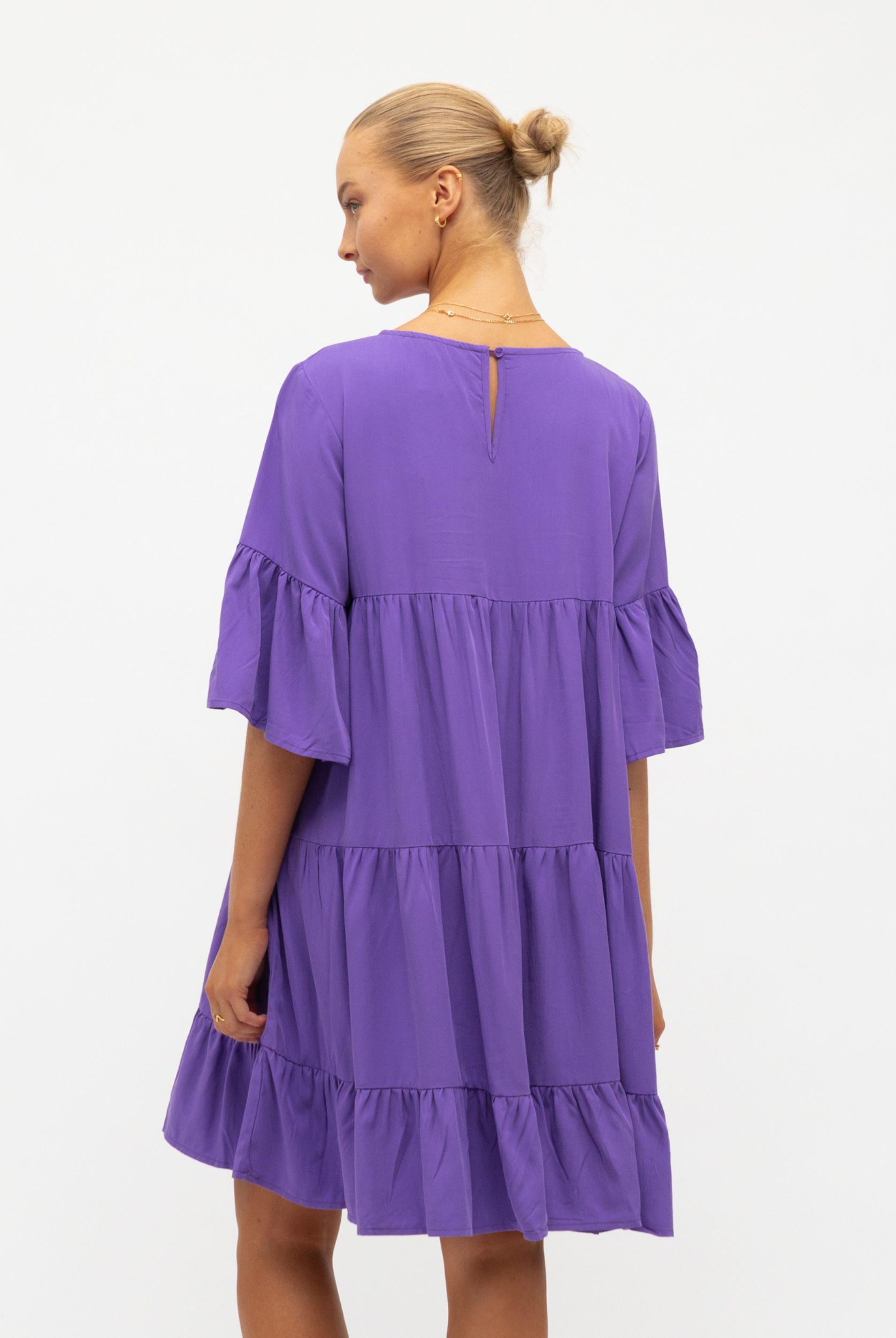 Model wearing purple tiered dress with a flattering mid length sleeve from label of love