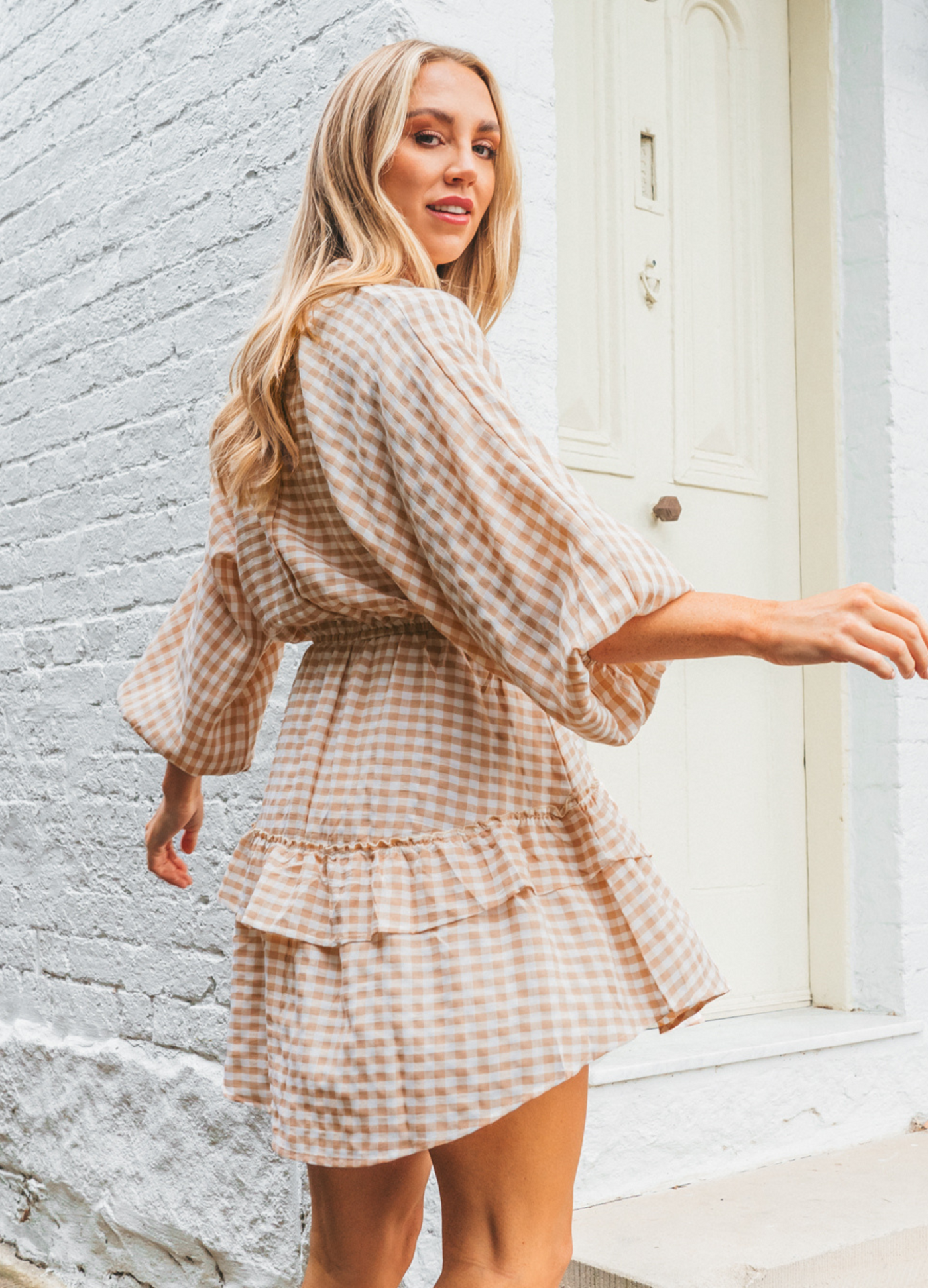 Model wearing neutral and white gingham shirt dress with functional button placket and elasticated waistband