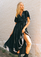 Model wearing black arabella maxi dress with short sleeve, wrap top and waist bel