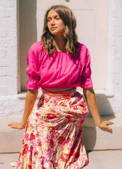 Model wearing the Riley Bright pink top and sitting down on a step