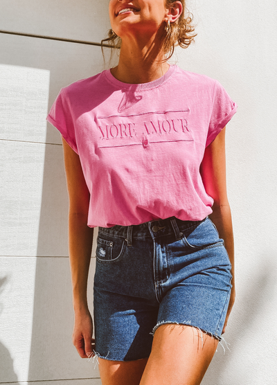Women smiling and wearing a pink tshirt and denim cut off shorts