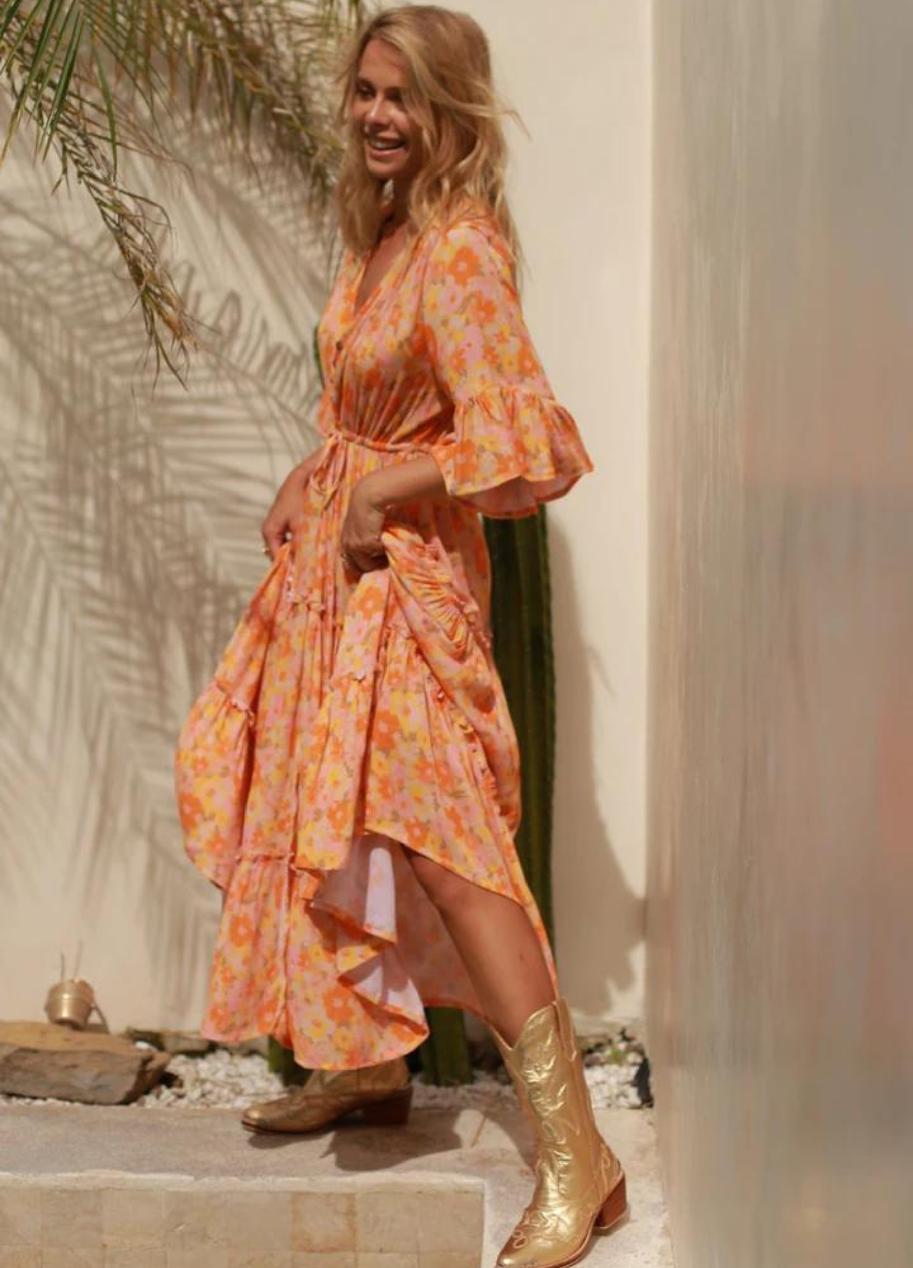 Model wearing orange floral print gown with button front and drawstring tie at waist with a mid length sleeve