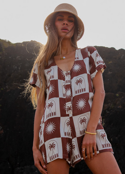 Woman wearing a chocolate and white palm print playsuit 