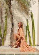 Model wearing orange floral print gown with button front and drawstring tie at waist with a mid length sleeve