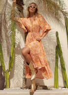 Model wearing orange floral print gown with button front and drawstring tie at waist with a mid length sleeve