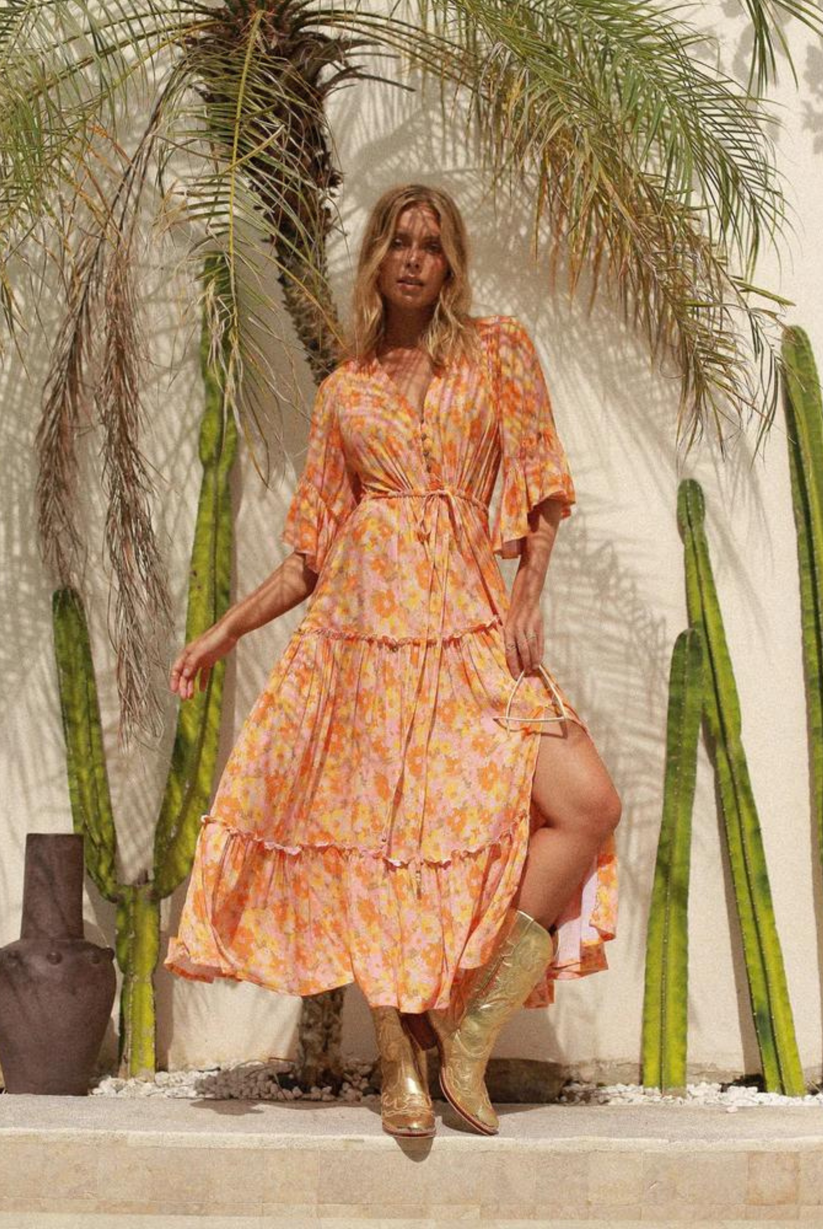 Model wearing orange floral print gown with button front and drawstring tie at waist with a mid length sleeve