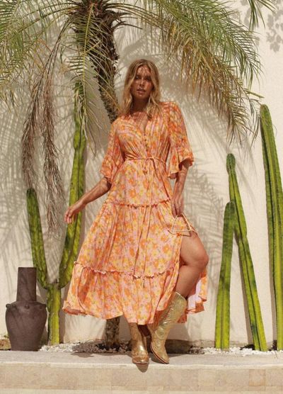 Model wearing orange floral print gown with button front and drawstring tie at waist with a mid length sleeve