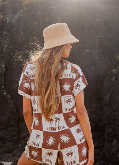 Woman wearing a chocolate and white palm print playsuit 