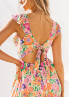 Model wearing bright floral colour dress with cut out at the back and buttons at the front