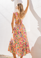 Model wearing bright floral colour dress with cut out at the back and buttons at the front