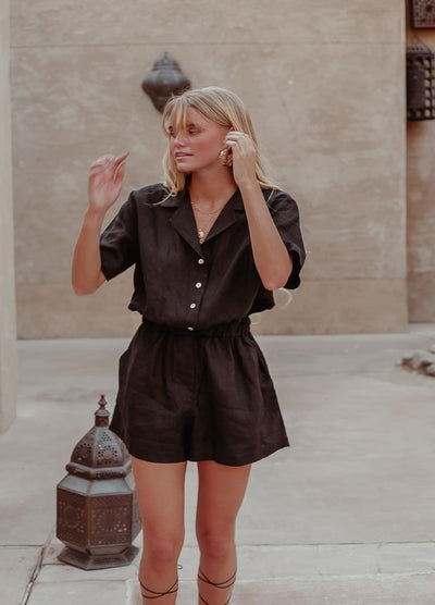 Woman with blonde hair wearing black linen playsuit