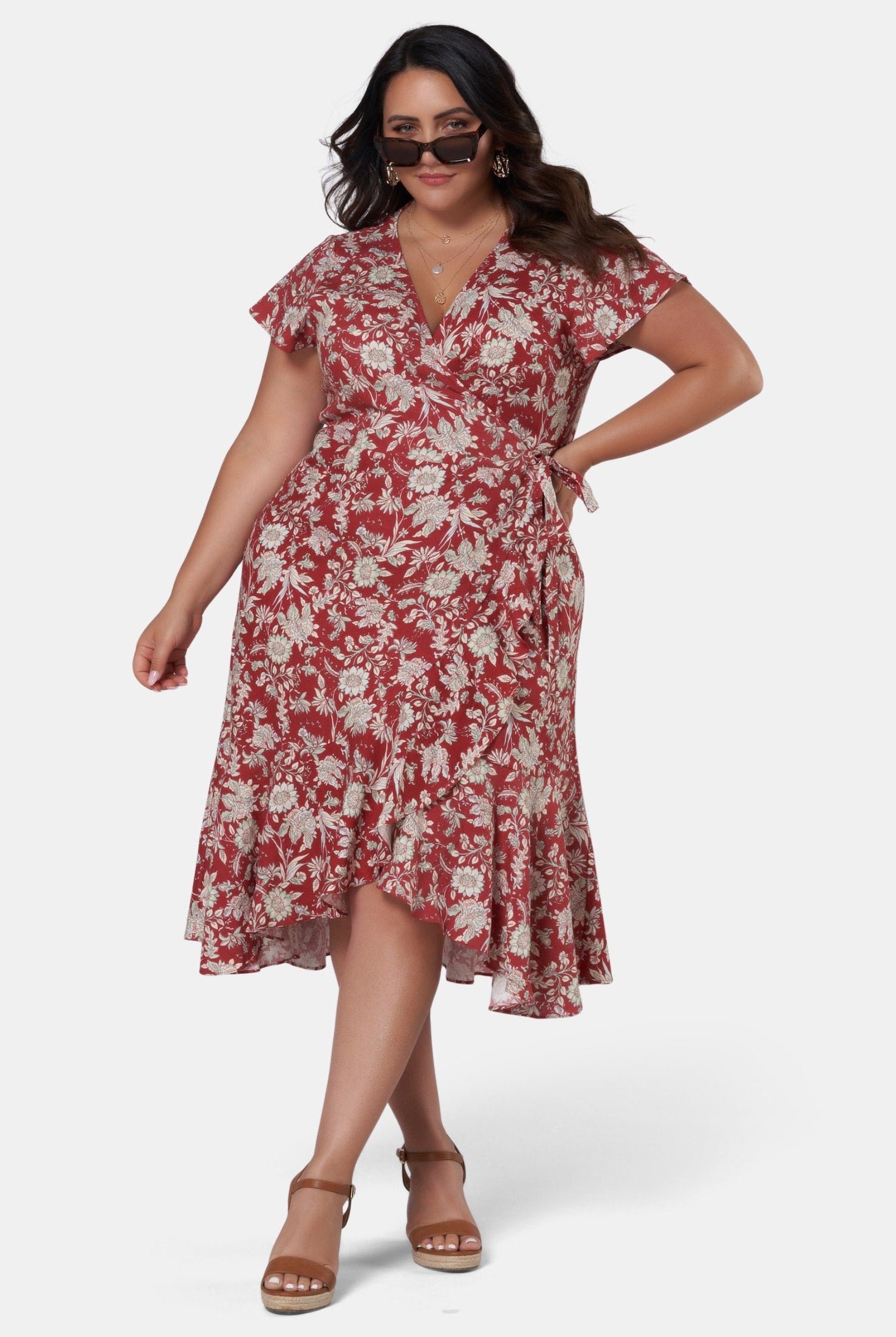 Brunette model wearing red base floral print wrap dress