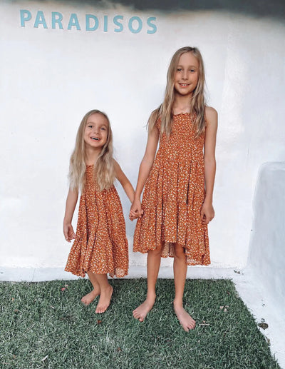 Rust based print with ditzy floral design in tiered style with hi lo hem