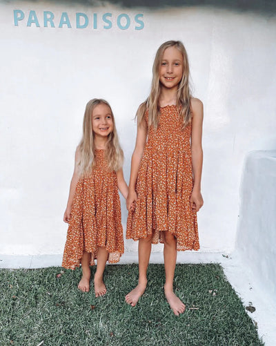 Rust based print with ditzy floral design in tiered style with hi lo hem
