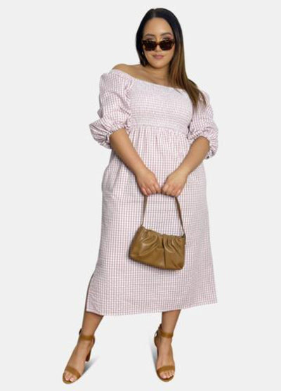 Model wearing pink gingham dress holding handbag