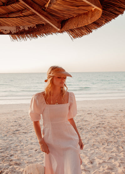 Blonde model wearing pale pink monte dress on a beach