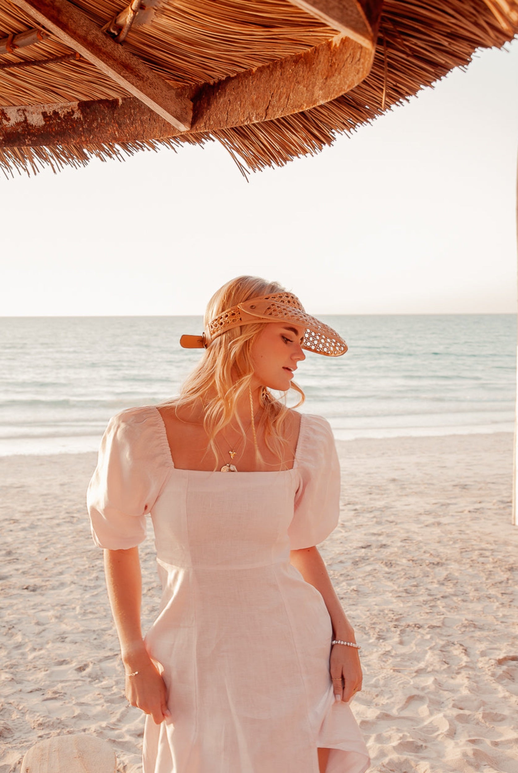 Blonde model wearing pale pink monte dress on a beach