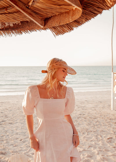 Blonde model wearing pale pink monte dress on a beach