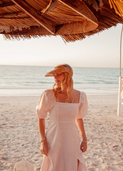 Blonde model wearing pale pink monte dress on a beach