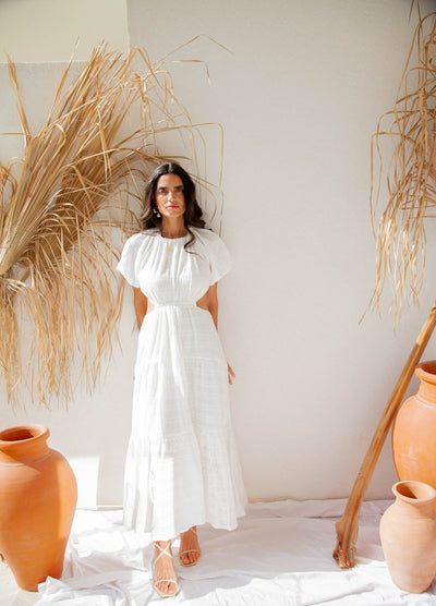 Woman standing by wall wearing maxi dress