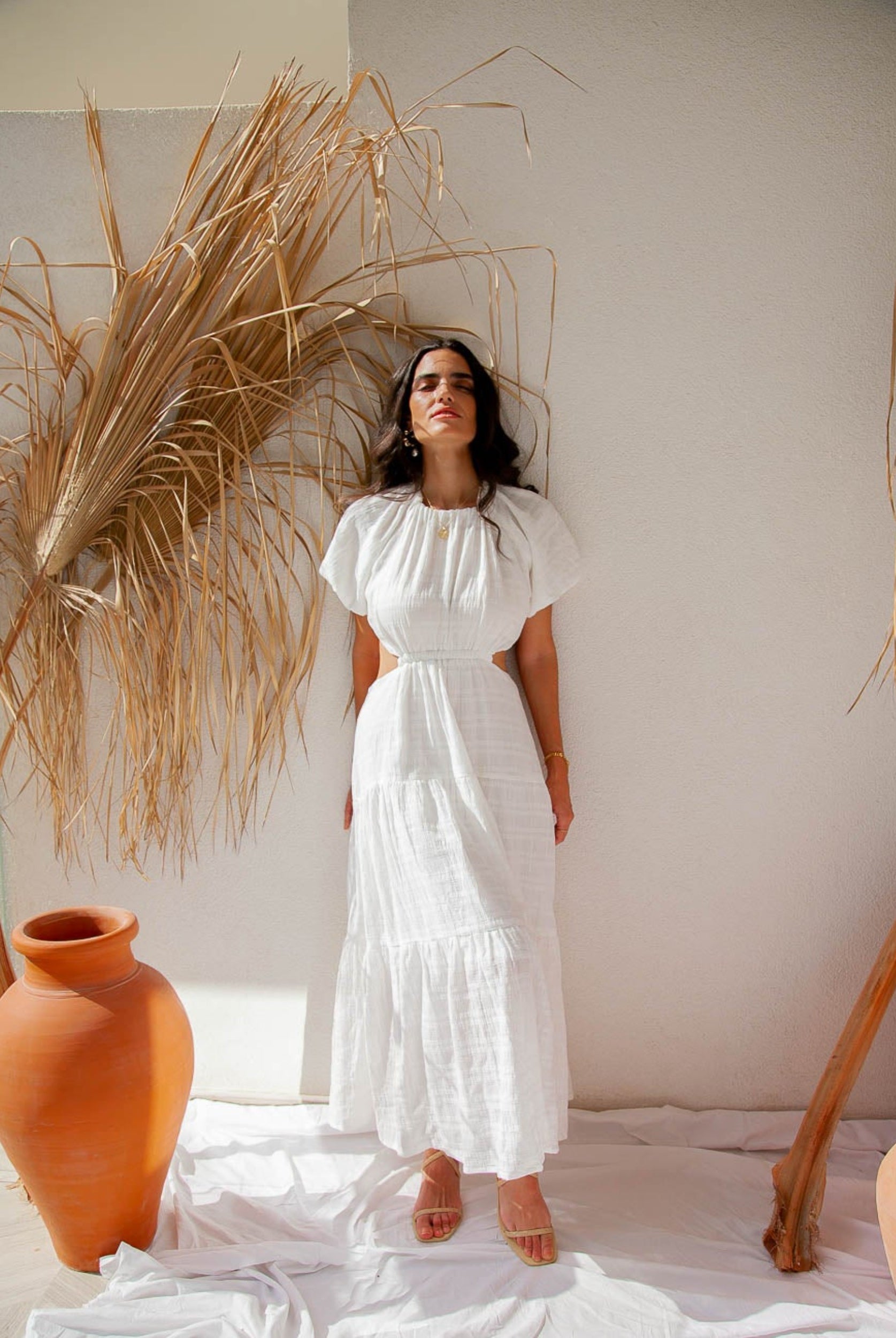 Woman standing by wall wearing white maxi dress