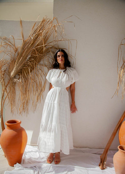 Woman standing near wall wearing white maxi dress