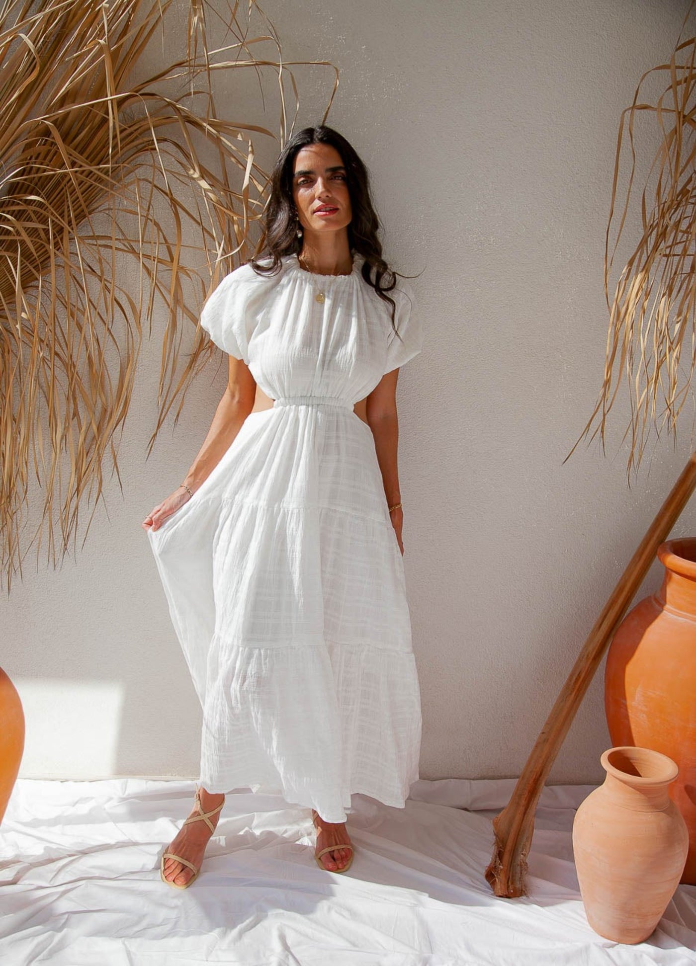 Woman standing near wall wearing white dress