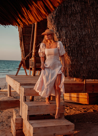 Blonde model wearing pale pink monte dress on a beach