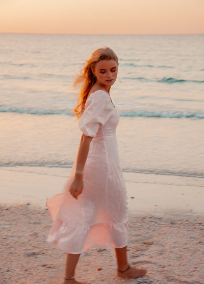 Blonde model wearing pale pink monte dress on a beach