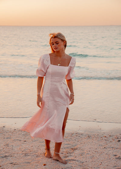 Blonde model wearing pale pink monte dress on a beach