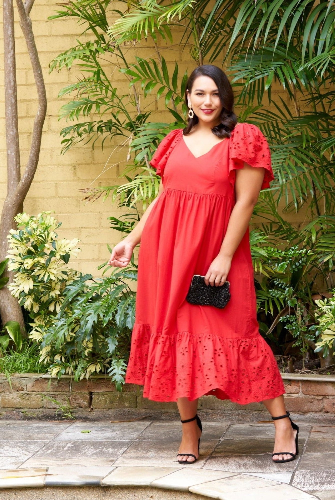 Model wearing red dress in tropical garden