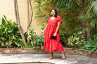 Model wearing red dress in tropical garden