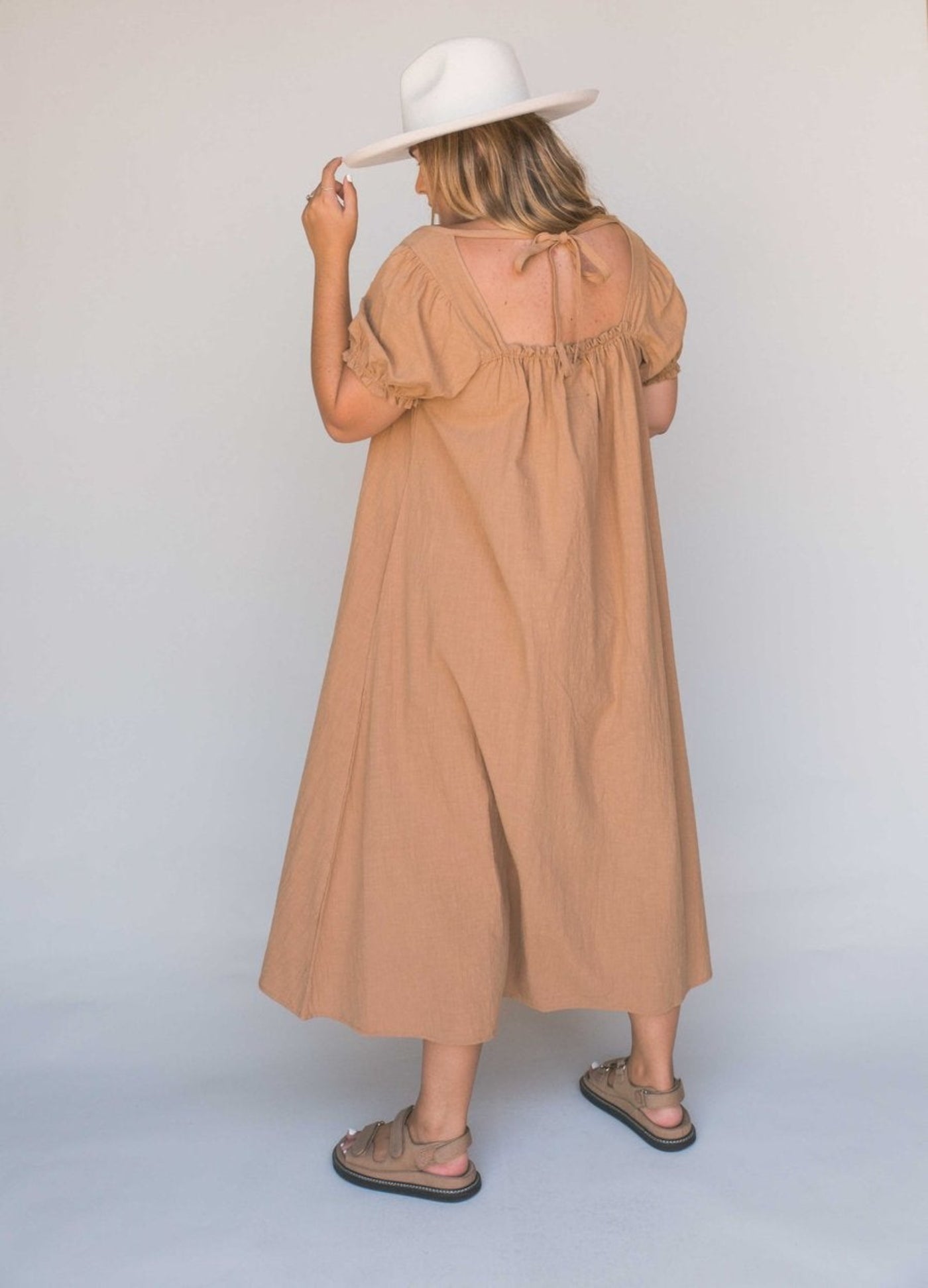 Model shot from the back wearing beige midi dress