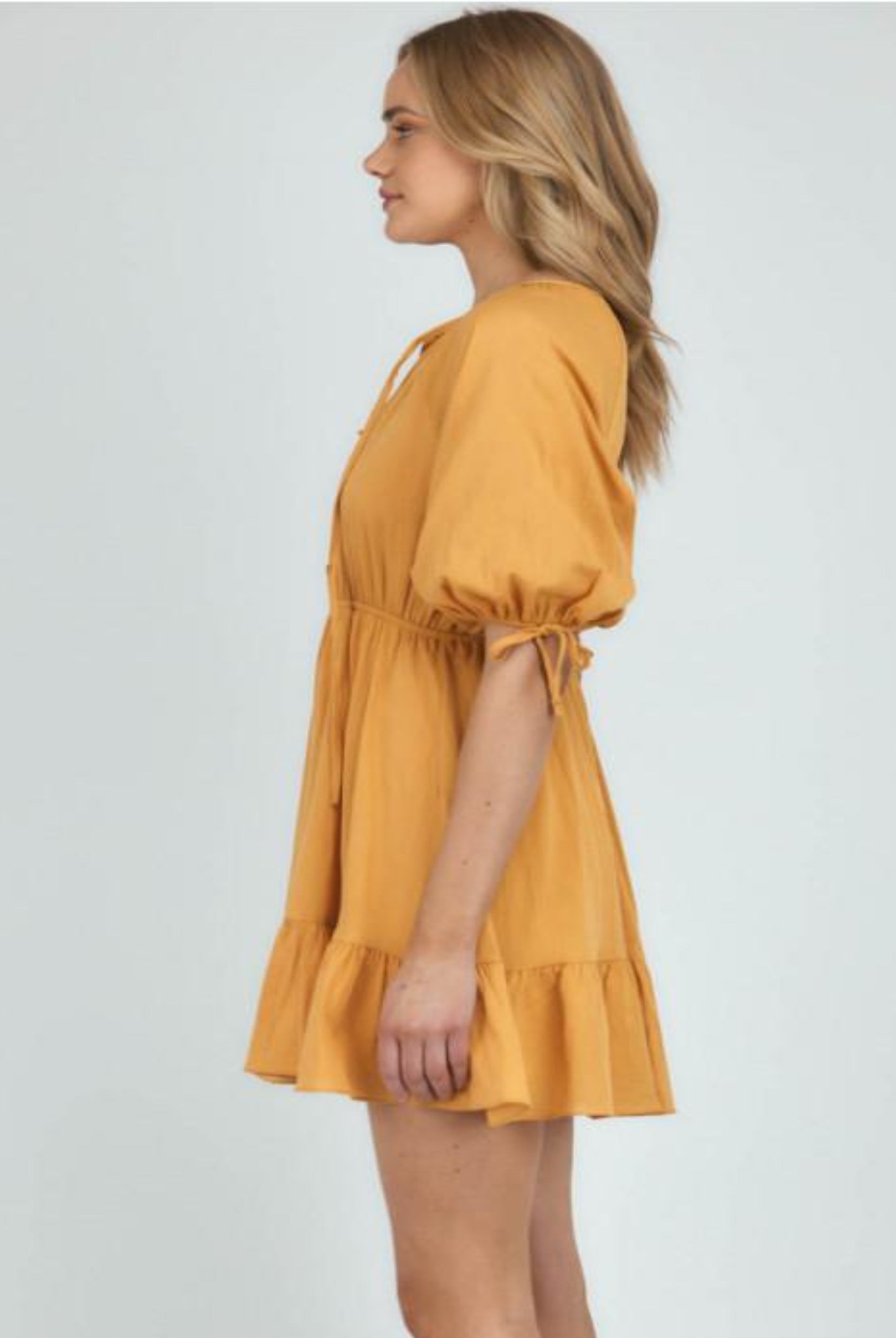 Blonde woman wearing yellow a line dress shot from side