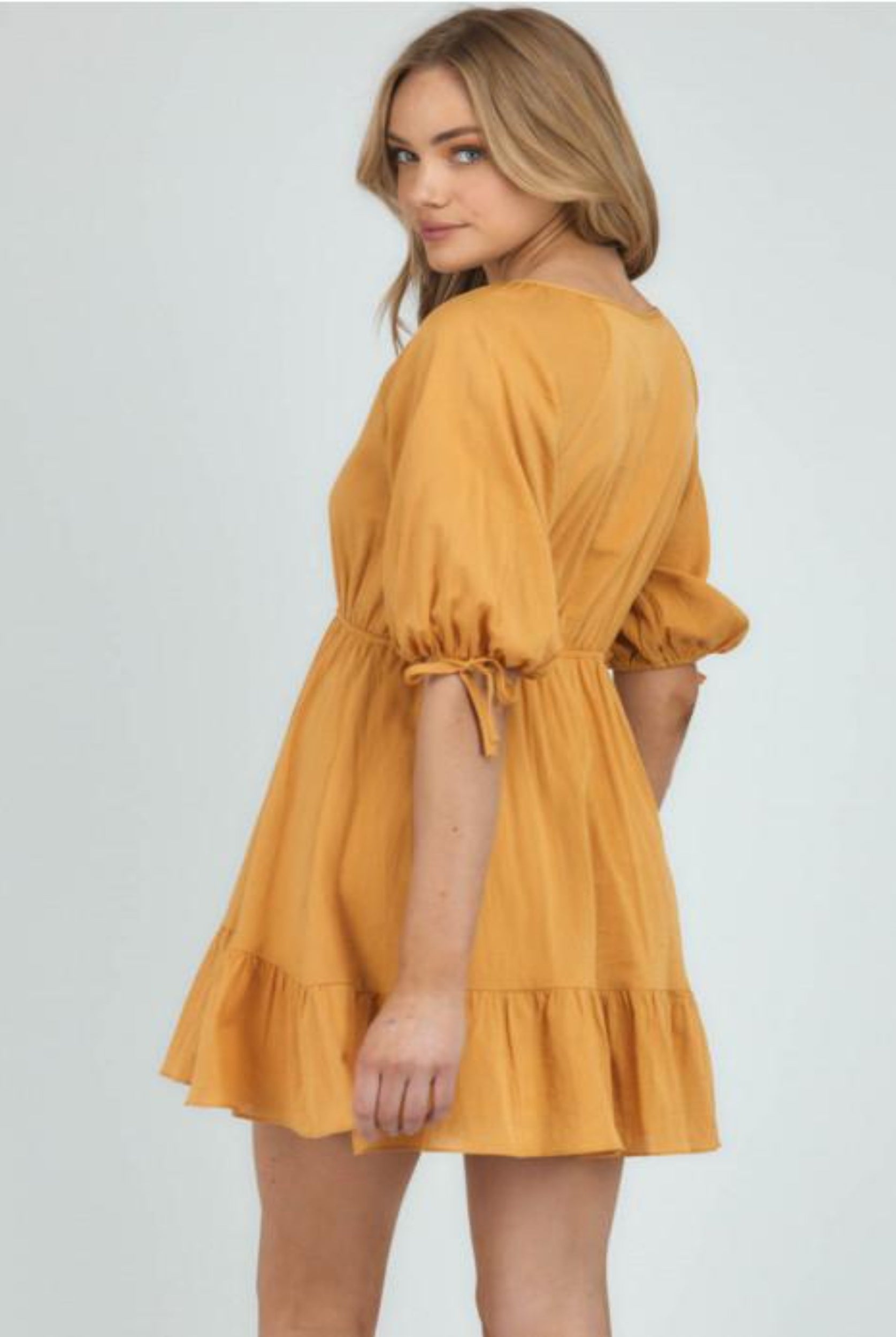Blonde woman wearing yellow a line dress looking back