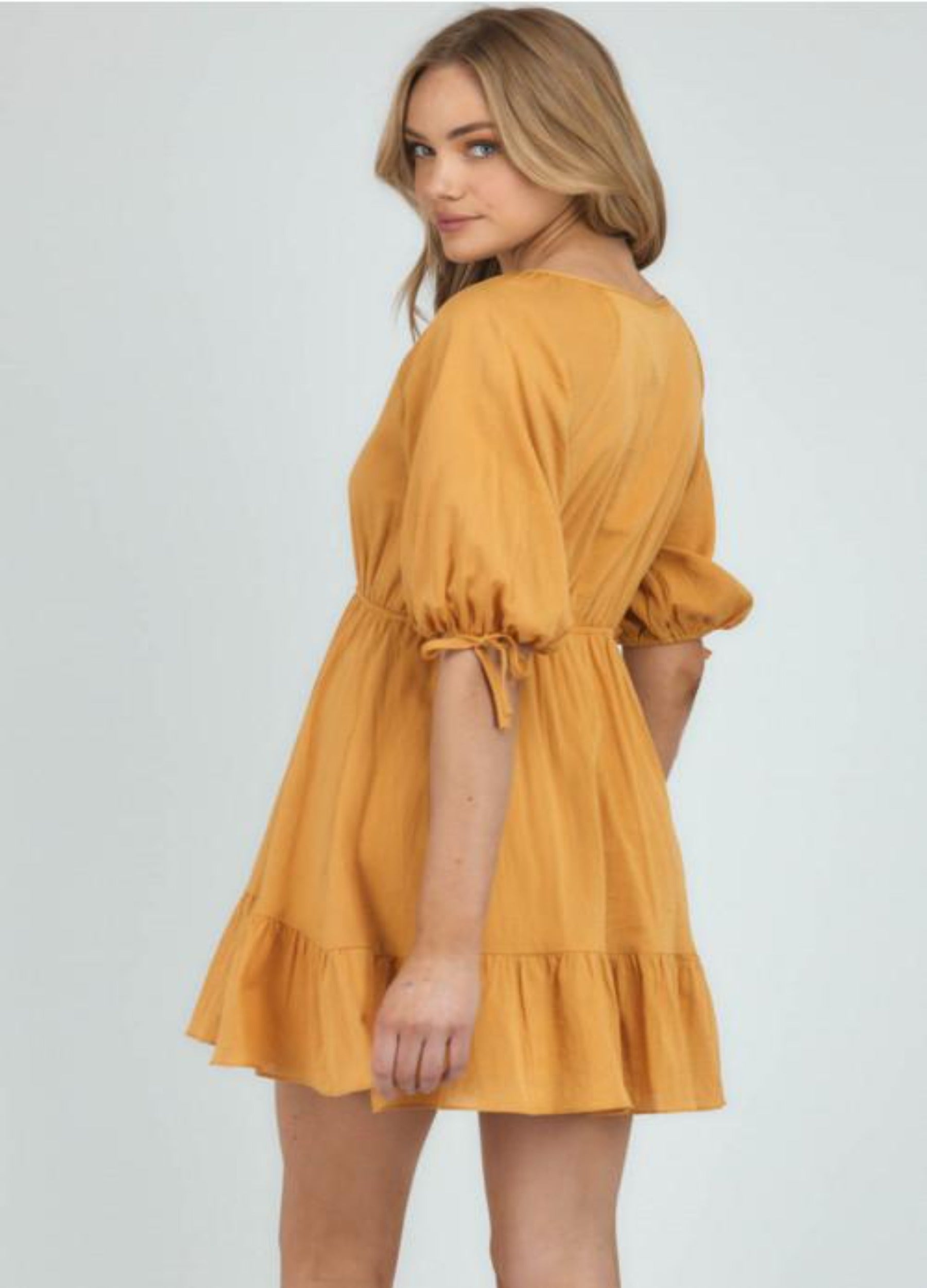 Blonde woman wearing yellow a line dress looking back